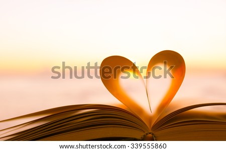Heart from a book page against a beautiful sunset