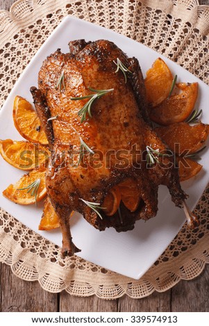 Delicious Roast duck with oranges and rosemary close up on a plate. vertical top view
