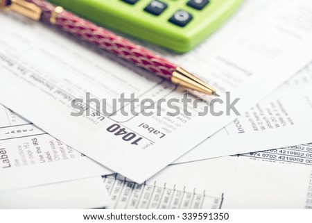 Calculating numbers for income tax return with pen, glasses and calculator