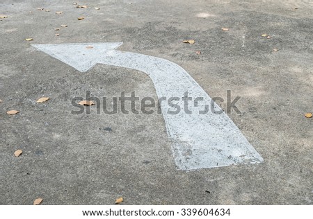 Closeup white painted arrow sign on cement street floor background
