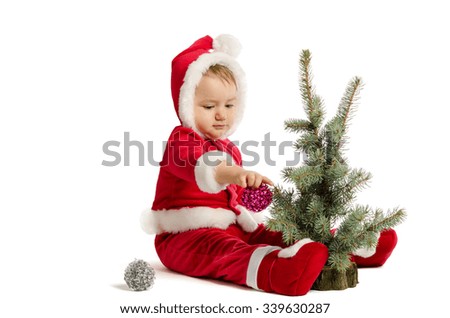 Funny baby in Santa Claus clothes  is decorating xmas tree on white background