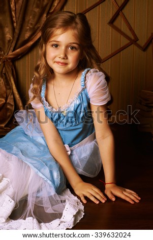 Little girl in a blue dress on the floor in room