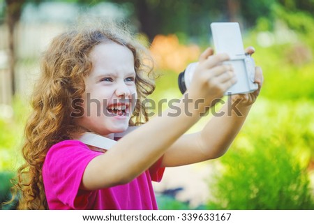 Laughing girl taking selfie with photo camera.