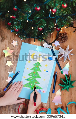 Girl drawing Christmas card with pine tree