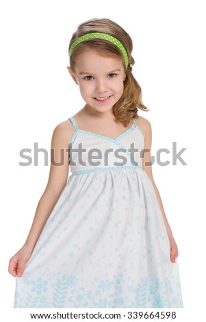 A smiling little girl in a fashion dress is standing against the white background