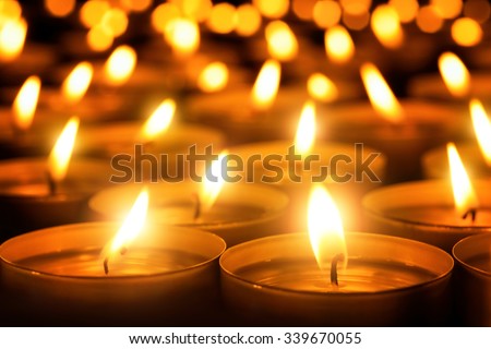Many candle flames glowing in the dark, create a spiritual atmosphere