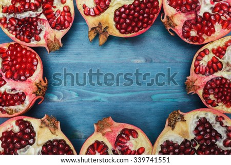 Cut in half pomegranate on a wooden blue surface: sources of vitamins and antioxidants in the winter, food for vegans