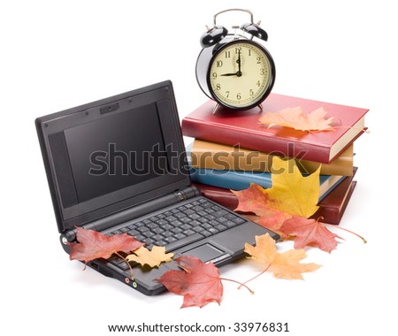 Pile of books, notebook, alarm clock and autumn leaves on a white background.
