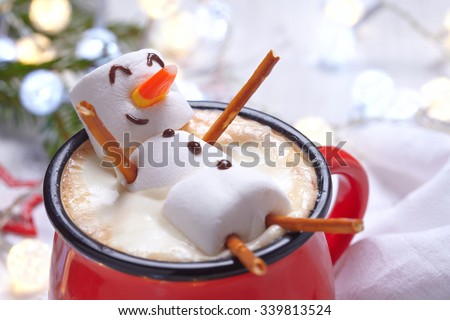 Red mug with hot chocolate with melted marshmallow snowman Royalty-Free Stock Photo #339813524
