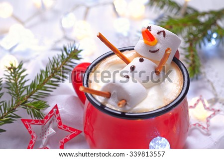 Red mug with hot chocolate with melted marshmallow snowman Royalty-Free Stock Photo #339813557