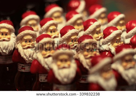 Closeup view of many bright small funny santa claus bottles with red cherry liquid in christmas costume as new year gift, horizontal picture