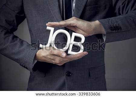 Businessman in suit with two hands in position to protect the word "JOB" (focus on hand, blur out the suit).