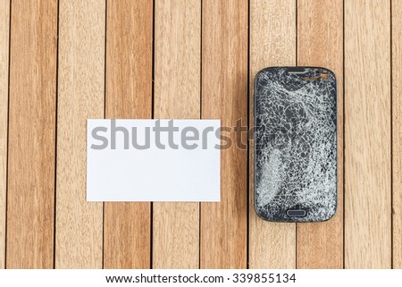 Top view broken of smart phone and blank paper on wooden table background