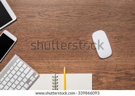 Office wooden table with notebook, yellow pencil, tablet, keyboard, mouse and smartphone, top view