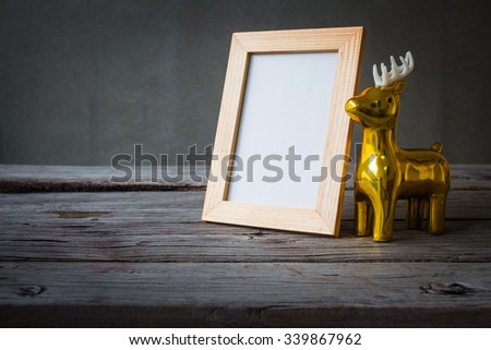 Vintage photo frame with golden deer, Christmas decoration on wooden table over grunge background
