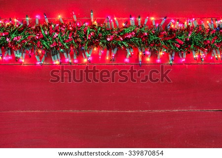 Blank rustic red wood sign with holiday lights and colorful red and green Christmas garland border