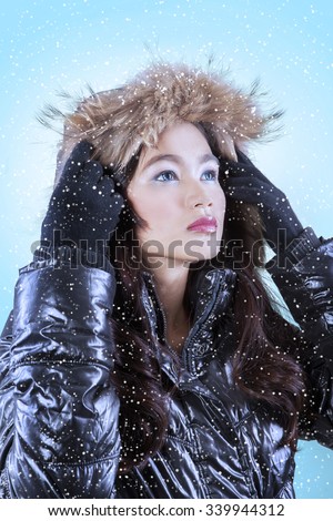 Beautiful young asian girl wearing jacket in snowy day and staring at copyspace