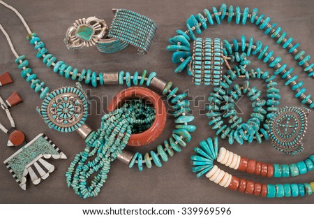 A collection of Native American Jewelry.A Santo Domingo Depression Era� Necklace, and Turquoise "Nugget" with silver beads, and Zuni and Navajo "Cuff" Bracelets, on a Grey Slate Background.
