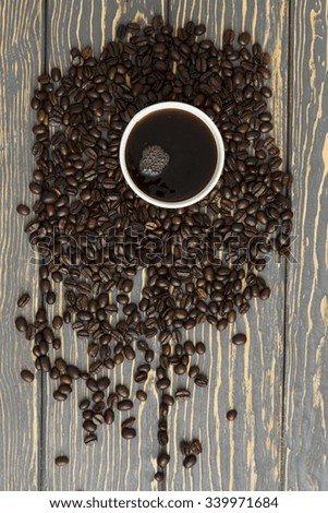 heap of coffee beans in cup on wood table