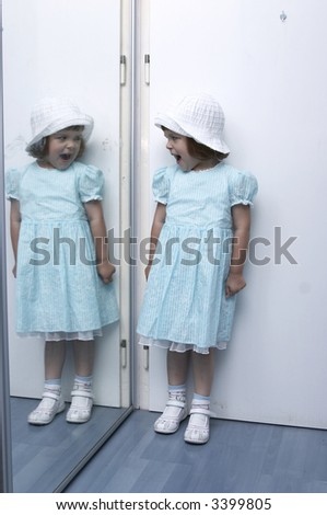 little girl, dressed up, and her twin in the mirror