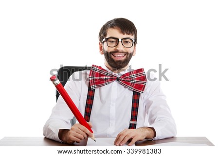 Funny old fashioned man sitting by a desk writing with big pencil.