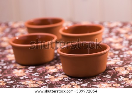 Four beautiful pottery artwork authentic bowls made of ecological raw material standing on floral background indoor closeup, horizontal picture