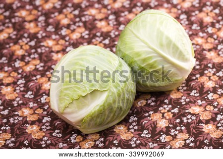 Pair of juicy tasty white headed cabbages vegetable healthy organic food laying on floral background studio closeup, horizontal picture