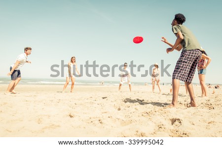 Group of friends playing with disc on the beach 