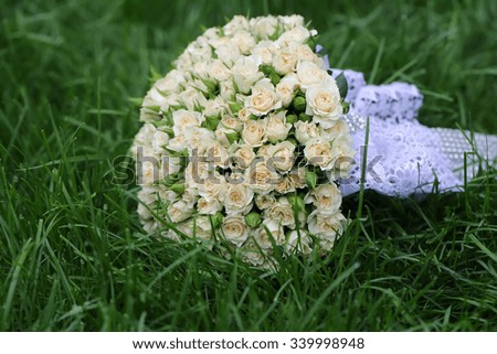 Closeup view of one beautiful fresh bright white yellow big wedding bouquet of rose flowers lying on green grass sunny day outdoor on natural background, horizonbtal picture