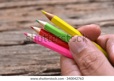 hand hold color pencils with wood background