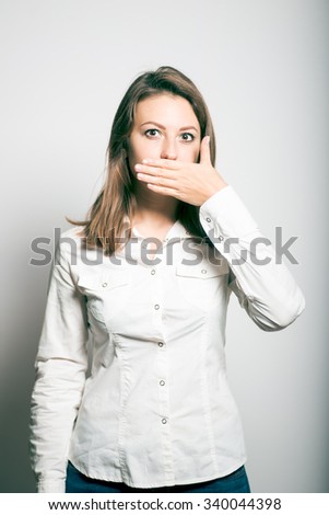 Business woman covers her mouth with his hand. studio photo on a gray background