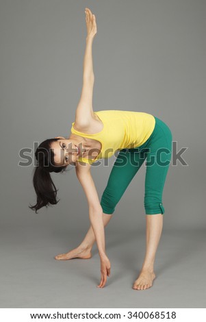 A flexible young happy woman reaching down to the floor.