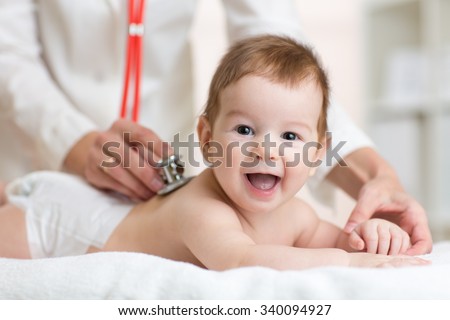 Pediatrician doctor examines baby boy with stethoscope checking heart beat.  Royalty-Free Stock Photo #340094927