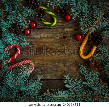 Christmas border with pine tree branches, cones, christmas decorations and candy cane on rustic wooden boards