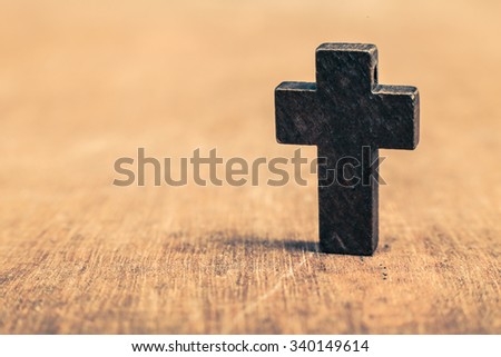 Old wooden cross standing on the rustic wooden background.
