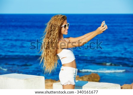 Blond kid teen girl photo selfie on smartphone in a beach at Mediterranean