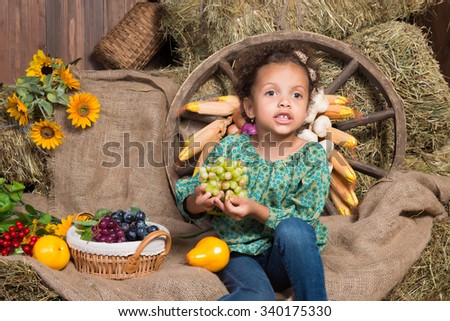 Cute  african girl sitting on straw on the background of a wooden wall