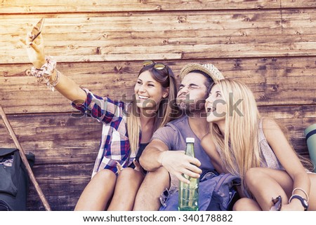 group of smiling friends taking funny selfie with smart phone