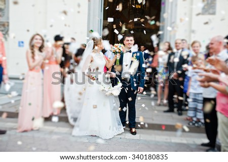wedding couple come out from church under petals of roses. blur effect