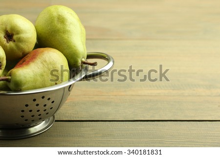 juicy green pears are in the strainer on wooden brown background
