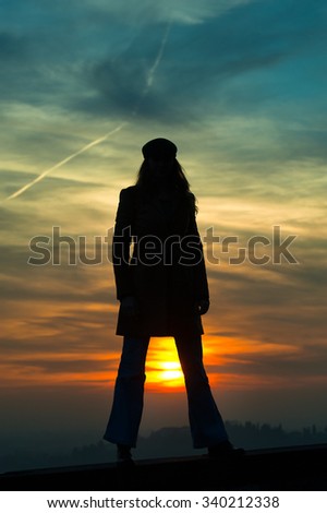 Girl standing with sun between legs in silhouette