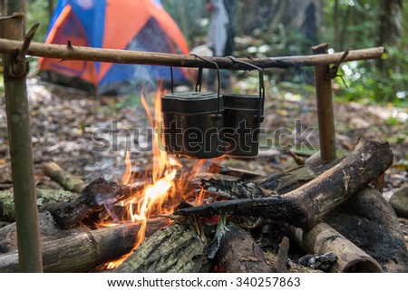 Rice cooking with army pot by using bonfire while camping in the forest. Royalty-Free Stock Photo #340257863