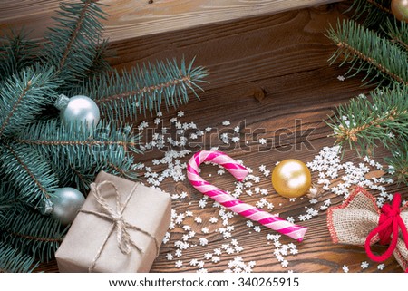 christmas gifts packaged in craft paper, pink candy cane, sprinkling as snowflakes, Santa's sack on wooden table. Christmas tree with silver and golden balls.