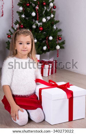 cute little girl with big gift box near Christmas tree at home