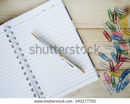 Blank notebook and one pen on wood background