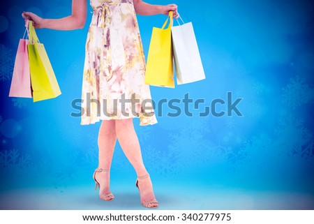 Elegant blonde with shopping bags against glowing christmas background