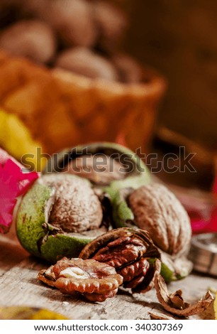 
Fresh walnuts in a green shell, autumn harvest, amid the fallen leaves, vintage wood background, selective focus