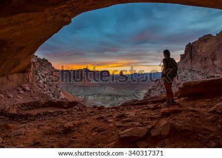 Girl Backpacker looking at beautiful sunset from inside of the False Kiva Canyonlands National Park Moab Utah USA Royalty-Free Stock Photo #340317371