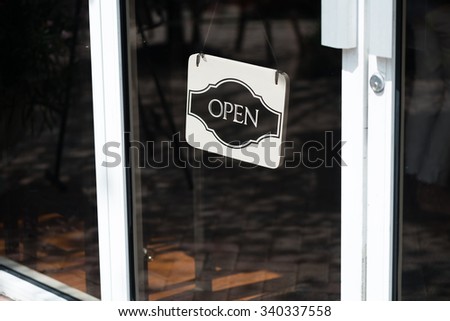 Black and White open sign hanging in store glass door