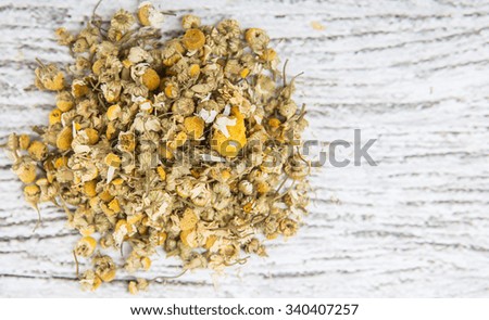 Dried chamomile herbal tea over wooden background